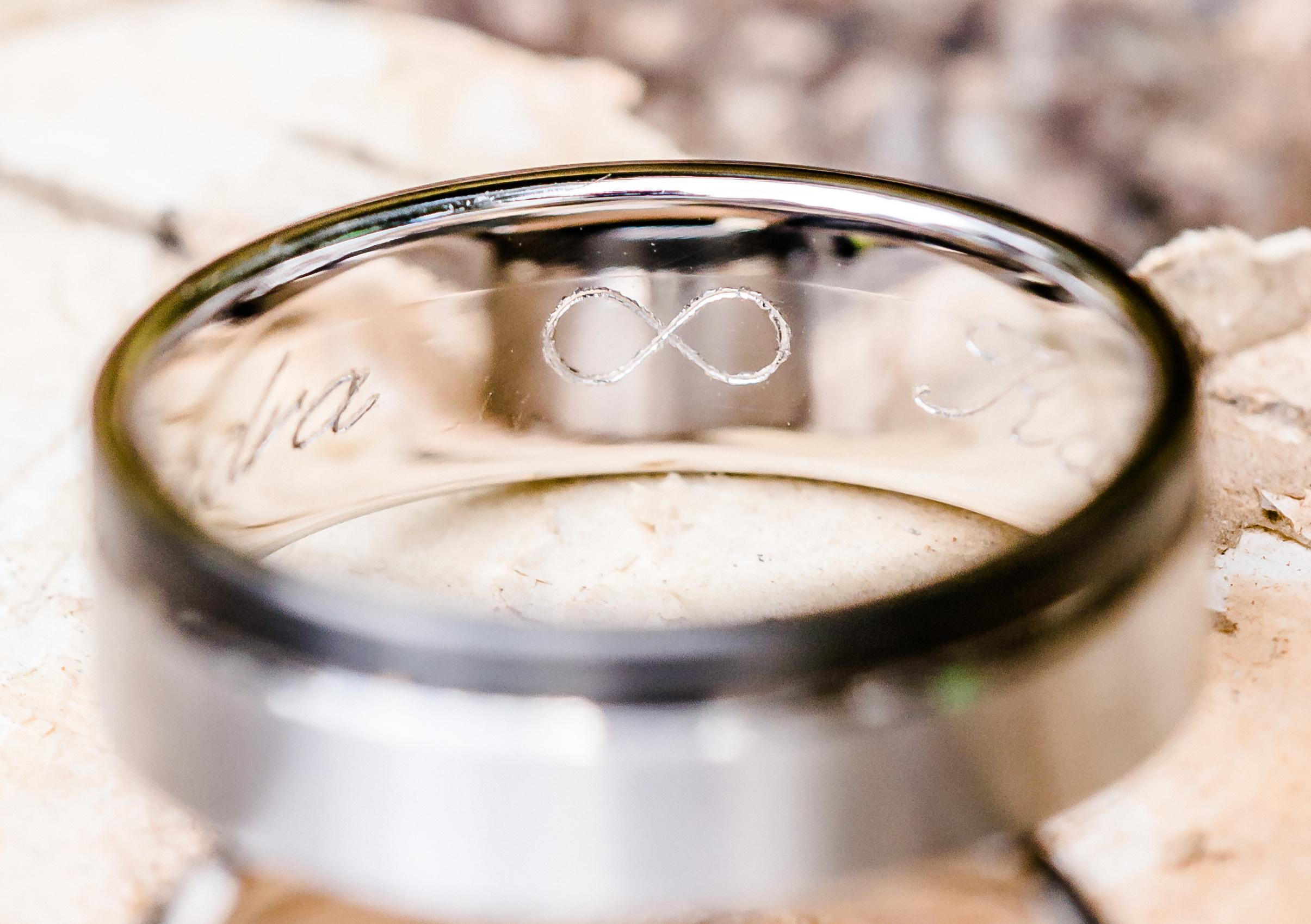 Nahaufnahme eines Eherings aus Silber mit Gravur und Unendlichkeits-Symbol auf hellem Hintergrund