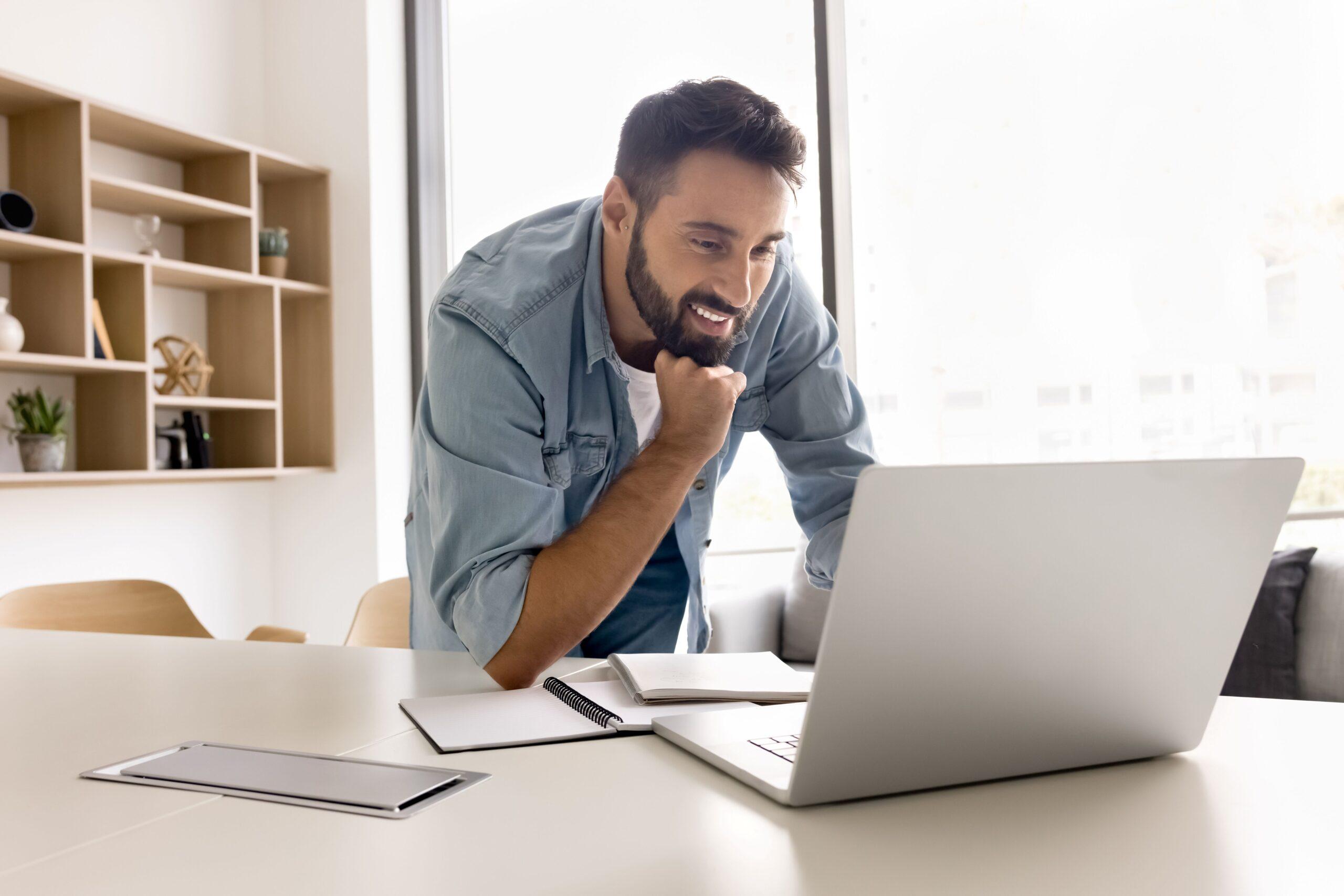 Ein Mann liest Texte auf dem Laptop und reagiert positiv